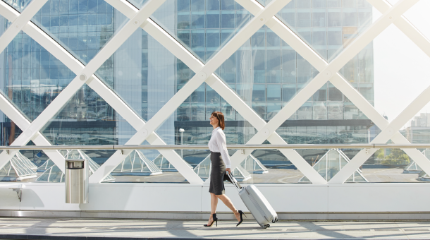 Woman walking over a bridge pulling a suitcase